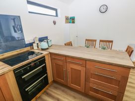 A kitchen with a countertop, oven, kettle, and dining table at Brookview Kingfisher in Haverfordwest