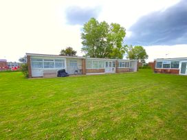 A bungalow with windows and grass area at Chalet 62 California, Norfolk