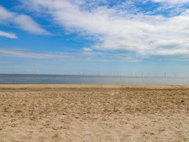 A beach with sand and water with wind turbines in the background at Chalet 62 California, Norfolk