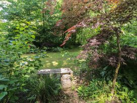 A garden with a bench surrounded by trees and plants at Brookview Goldfinch in Haverfordwest