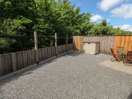 An outdoor garden area with a gravel surface and wooden furniture at Brookview Goldfinch in Haverfordwest