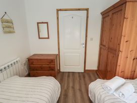 A bedroom with two beds and a wooden wardrobe at Brookview Goldfinch in Haverfordwest