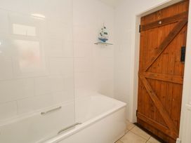 A bathroom with a bathtub and a wooden door at NO 10 Fortuneswell