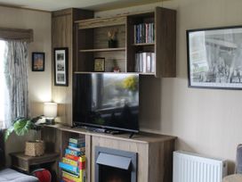 A living room with a television, shelves, and a lamp at Kent Coast Holiday Park - Holiday Accommodation 22252, Rochester, Kent
