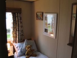 A bedroom with a bed, teddy bear, and wall art at Kent Coast Holiday Park - Holiday Accommodation 22252 in Rochester, Kent