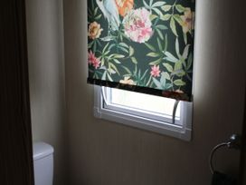 A bathroom with a toilet and a window covered by a floral roller blind at Kent Coast Holiday Park - Holiday Accommodation 22252, Rochester, Kent