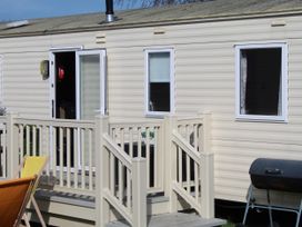 An outdoor view of a mobile home with steps and barbecue at Kent Coast Holiday Park - Holiday Accommodation 22252, Rochester, Kent