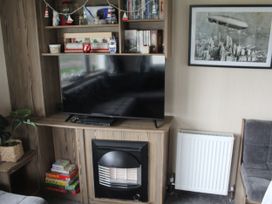 A living room with a television and shelves at Kent Coast Holiday Park - Holiday Accommodation 22252, Rochester, Kent