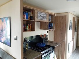 A kitchen with stove, utensils, and shelves at Kent Coast Holiday Park - Holiday Accommodation 22252, Rochester, Kent