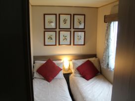 A bedroom with two beds and framed pictures at Kent Coast Holiday Park - Holiday Accommodation 22252, Rochester, Kent