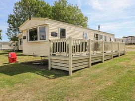 A caravan with a deck in front of it at Estuary View in Allhallows
