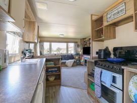 A kitchen with appliances and living area at Estuary View in Allhallows