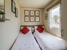 A bedroom with twin beds and framed artwork at Estuary View in Allhallows