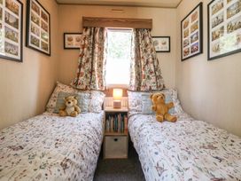 A bedroom with two beds and a bedside table at Estuary View in Allhallows