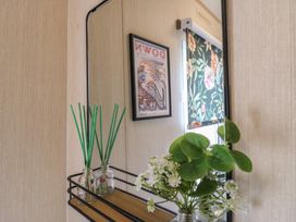 A shelf with a vase and a mirror at Estuary View in Allhallows