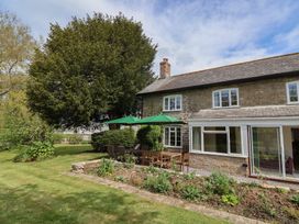 A garden with table and chairs next to a house at Harbins Farm in Glanvilles Wootton Nr. Sherborne
