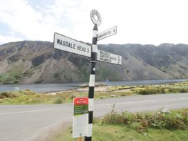 A signpost with distance markers near a lake and mountains at Pandora Holmrook