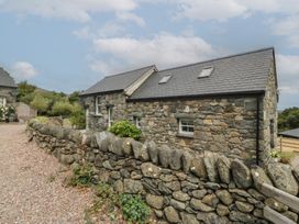 A stone house with a rock wall and garden at The Byre Conwy