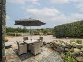 A patio with a table and chairs under an umbrella at The Byre in Conwy