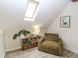 A snug with an armchair and bookshelf at The Byre in Conwy