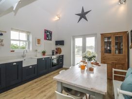 A kitchen with a sink, oven, table, and chairs at The Byre in Conwy