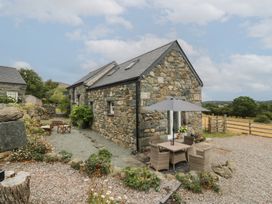 An outdoor area with a stone building and seating at The Byre in Conwy
