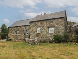 A stone building with a table and chairs in the garden at The Byre in Conwy