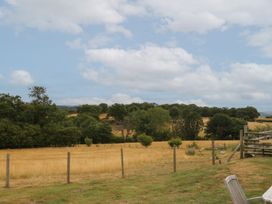 A field with trees and a fence at The Byre in Conwy