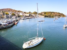 A sailboat in a harbor with houses and mountain in the background at The Byre in Conwy