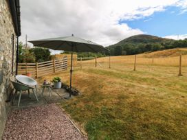 A patio with chairs and an umbrella at Little Oak near Tal-Y-Bont