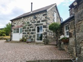 An outdoor view of a stone house with a gate and gravel path at Little Oak near Tal-Y-Bont