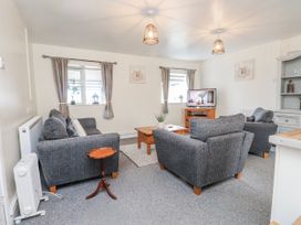 A living room with sofa, table, and television at Hen Fecws near Rhoshirwaun