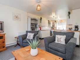 A living room with a coffee table and kitchen area at Hen Fecws in Rhoshirwaun near Sarn Meyllteyrn