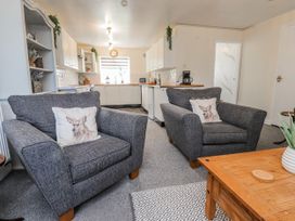 A living room with gray sofas and a kitchen in the background at Hen Fecws Rhoshirwaun near Sarn Meyllteyrn