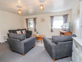 A living room with a sofa, coffee table, and television at Hen Fecws Rhoshirwaun near Sarn Meyllteyrn