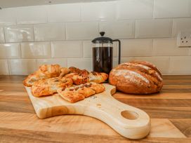 A cutting board with pastries and bread in a kitchen at Hen Fecws Rhoshirwaun near Sarn Meyllteyrn
