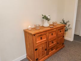 A wooden sideboard with a candle and a flower vase in a hallway at Hen Fecws Rhoshirwaun near Sarn Meyllteyrn