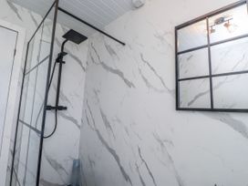 A bathroom with a glass shower enclosure and a mirror at Hen Fecws Rhoshirwaun near Sarn Meyllteyrn