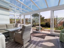 A conservatory with a glass roof and seating area at Tregoning in Lostwithiel