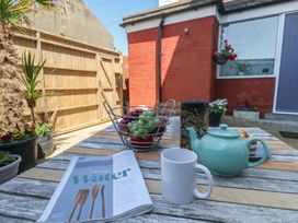 An outdoor area with a table, mugs, a teapot, and a basket of grapes at Tipsy Turtle in Weymouth