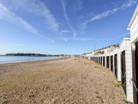 A view of beach huts along a pebbled beach at Rose Cottage in Osmington