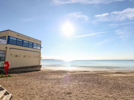 A beach with a building and water at Rose Cottage in Osmington