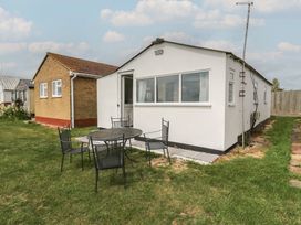 A house with a table and chairs on grass at Watersmeet - 85 @ Park Avenue Holiday Village, Leysdown-On-Sea, Kent