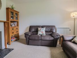 A living room with a sofa, cabinet, and lamp at 2 North Road in Maiden Newton, Dorset