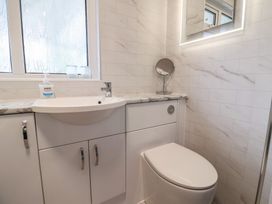 A bathroom with a sink, toilet, mirror, and window at 2 North Road, Maiden Newton, Dorset