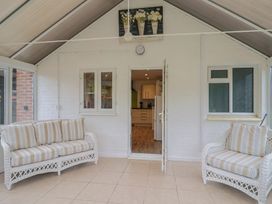 A conservatory with couches and a door leading to a kitchen at 2 North Road Maiden Newton, Dorset