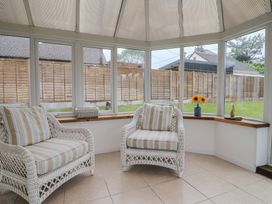 A conservatory with armchairs and a vase of sunflowers at 2 North Road Maiden Newton, Dorset