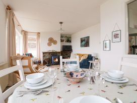 A dining room with a table set and a sofa in the background at Wootton Gray in Penzance