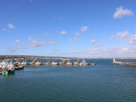 A view of fishing boats at the harbor with a lighthouse at Wootton Gray in Penzance