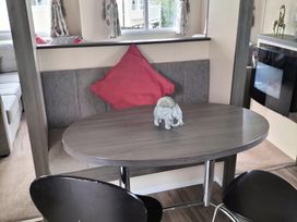 A dining area with table and bench seating at Beverley Bay Holiday Park - Holiday Accommodation 333, Paignton